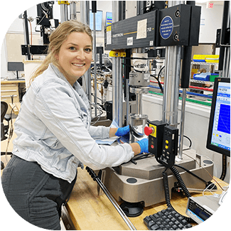 Technician Smiling at the Camera as She Prepares a Sample for Tensile Testing