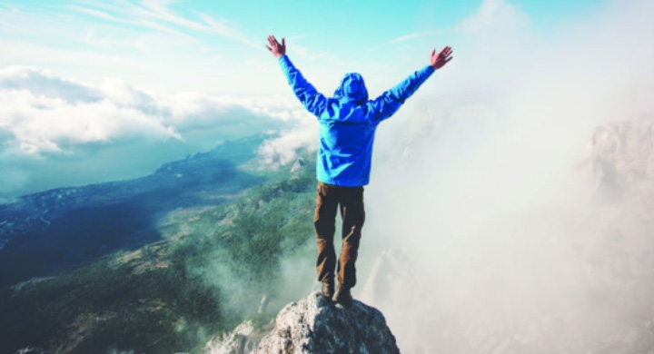 Stock Image of Climber at Top of Mountain, Arms Raised